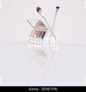 A multicolor eyeshadow palette with a soft makeup brushes resting against it, various pressed shades arranged in a compact case. The beauty product is Stock Photo