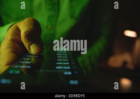 Hand holding smartphone displaying investment data and global stock exchange during night Stock Photo