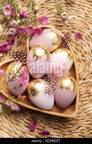 Easter decor. Easter eggs painted in gold in a heart-shaped wooden bowl. The concept of preparation for the celebration. Stock Photo