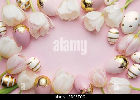 Easter golden eggs and pink tulips on pink background. Top view. Happy Easter composition. Greeting card. Stock Photo