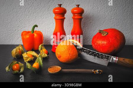A pumkin, orange pepper belle, physalis fruits on a slate countertop Stock Photo
