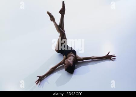 Ballerina lying on floor with legs raised and arms extended outward Stock Photo
