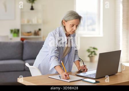 Senior woman working, eleder lady studying at home with laptop from remote location Stock Photo