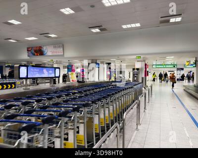 Manchester, UK - November 07, 2025: Crowded airport scene in Manchester with carts, signage, and passengers preparing for travel. Stock Photo