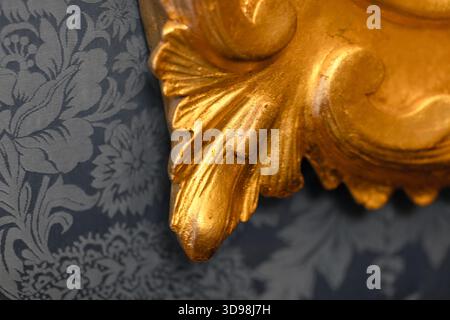 Close-up of a gilded decorative frame corner set against gray damask wallpaper, showcasing craftsmanship, luxury, and classic elegance ideal for inter Stock Photo
