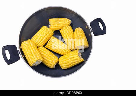 Cooking pot with boiled corn cobs. Fresh yellow boiled corn cobs halves in a pot, viewed from directly above on white background. Top view, nobody Stock Photo