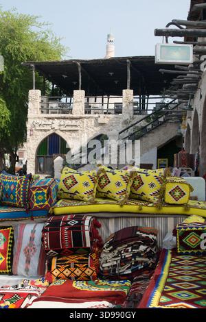 Brightly colored cushions and textiles are displayed at Souq Waqif in Doha, showcasing local craftsmanship in a bustling market setting. Stock Photo
