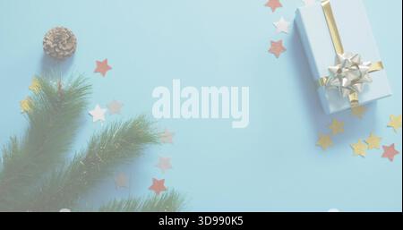 Sitting light-blue-gift gold-ribbon silver-bow on pale-blue surface firsprig cone stars, copy space Stock Photo