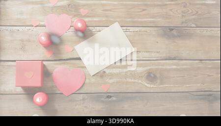 Displaying Valentine cluster on rustic wood table, with blank white card, pink hearts and gift box Stock Photo