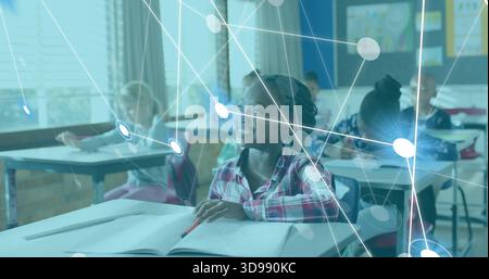 Smiling girl in pink plaid shirt writing at desk in classroom with notebook and digital overlay Stock Photo