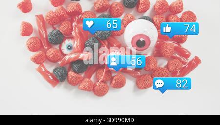 Displaying red and black gummy pile with licorice and plastic eyes on white backdrop, blue bubbles Stock Photo