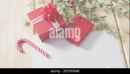 Displaying two red gift boxes with ribbons on light wooden table, candy cane and foliage Stock Photo