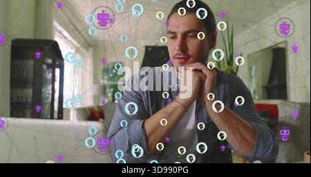 Thinking man sitting at table at home, wearing gray shirt over white tee, viewing network overlay Stock Photo