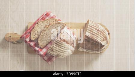 Showing two rustic sourdough loaves resting on light wood table, with cutting boards, gingham cloth Stock Photo
