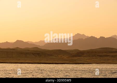 Beautiful yellow sunset on the red sea. mountains in the fog. Stock Photo