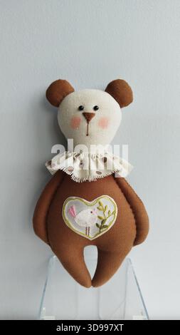 Soft handmade brown bear toy with lace collar and heart applique, simple studio look Stock Photo