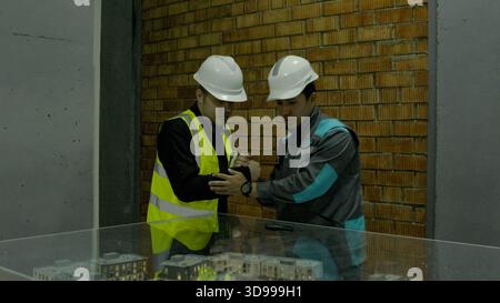 Construction workers in helmets discussing plans on the job site with equipment Stock Photo