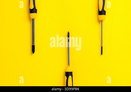 Screwdrivers arranged on a vibrant yellow background for a minimalist design Stock Photo