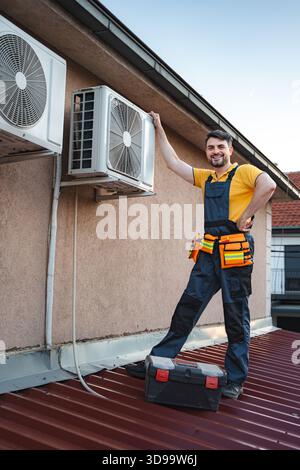 HVAC technician installing an air conditioner on a roof Stock Photo