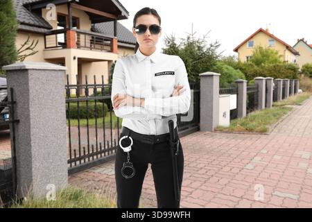 Security guard in uniform near house outdoors. Private property protection Stock Photo
