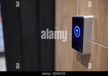 This is a modern smart touch sensor device installed on a wall, featuring a blue LED indicator Stock Photo