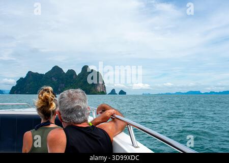 Happy couple sitting on a boat together on holiday in Phuket, Thailand. Man and woman looking at island from yacht in Phi Phi Islands Stock Photo