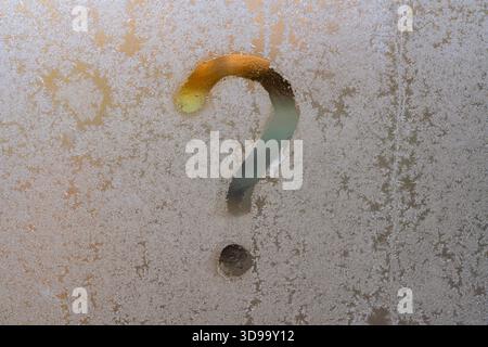 The question mark drawn on a frozen glass window. Frost patterns on window glass with question mark in winter, close up Stock Photo