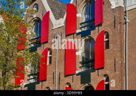 Historic Brick Building With Bright Red Shutters and Arched Windows With Urban Facade in Amsterdam, Holland. Stock Photo