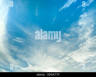 Bright blue sky with scattered soft clouds and gentle atmospheric texture. Stock Photo