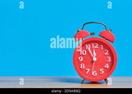 Red alarm clock on wooden table and blue background with copy space Stock Photo