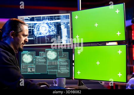 Hacker installing spyware using green screen PC and AI to secretly gather data about user activity. Rogue developer coding exploits using chroma key computer to gain unauthorized access Stock Photo
