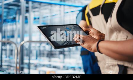 Photovoltaic smart factory specialist uses tablet to design production lines in CAD software. Industry 4.0 solar panels plant employee uses device to optimize floor layouts, camera A close up Stock Photo