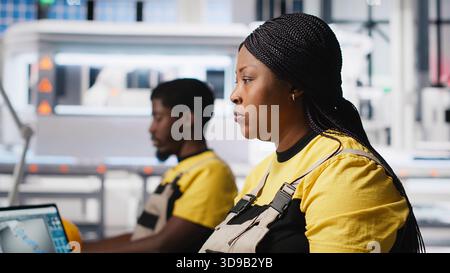 Black engineer testing solar technology at desk in renewable energy facility, focusing on software troubleshooting and performance metrics. Supports eco friendly industrial operations. Camera A. Stock Photo