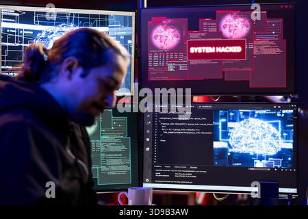 Hacker getting system hacked popup alert on computer display screen after using artificial intelligence malware software. Evil man in underground HQ trying to hide online activity after stealing data Stock Photo