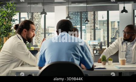 Health specialists and medics collaborating in conference room. Healthcare staff brainstorming treatment ideas and wellness through teamwork and communication in boardroom. Stock Photo