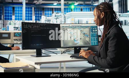 Photovoltaics factory programmer coding app monitoring system performance. Solar panels manufacturing plant system administrator writing code tracking energy production and efficiency, camera A Stock Photo