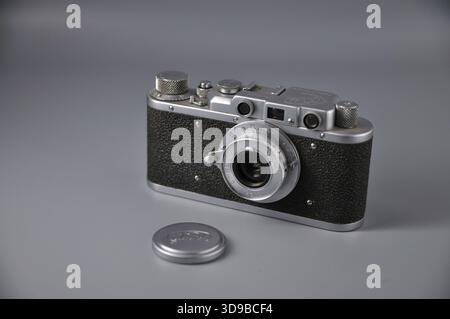 Classic metal rangefinder camera with textured body and lens cap, ideal for collectors and analog photography. Stock Photo