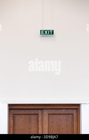 Emergency exit sign above the door. Clean and simple emergency exit sign on neutral background. Copy space. Stock Photo