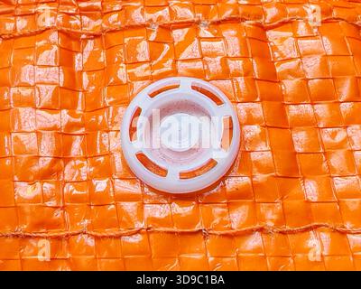 Close-up of White Air Valve on Wrinkled Orange Woven Plastic Storage Bag Texture for Packing, Travel and Vacuum Concept Stock Photo