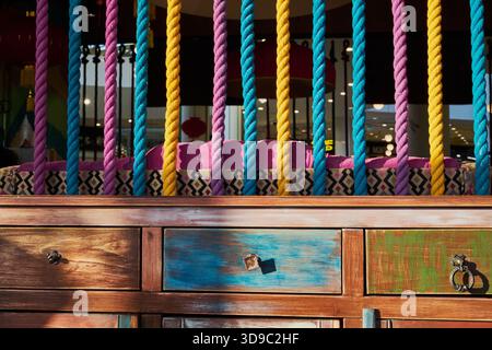 Colorful ropes and distressed wooden drawers forming vibrant, bohemian-inspired furniture piece Stock Photo