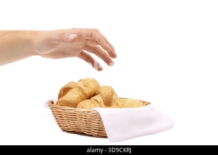 Hand reaches for the croissants in a basket. White background Stock Photo