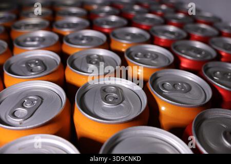 Close up perspective of many orange and red aluminum soda cans arranged in pattern. An industrial background of empty beverage containers ready for re Stock Photo