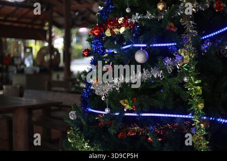 Festive decorated christmas tree glows with blue light and shiny ornament. This beautiful winter holiday celebration at night brings joyful and cozy a Stock Photo