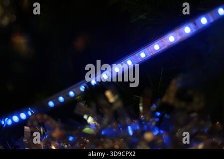 Glowing blue LED strip light shines brightly in dark. Modern, vibrant technology provides cool, futuristic illumination over blurred, reflective backg Stock Photo