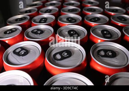 Top view of many red aluminum can for soda beverage on factory production line. Close up showing mass manufacturing of soft drink packaging with repet Stock Photo