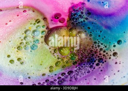 Colorful abstract macro of swirling bubbles and foam in vibrant pink, blue, green, and yellow tones. Stock Photo