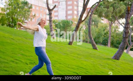 Happy senior woman enjoying and dancing in a city park Stock Photo