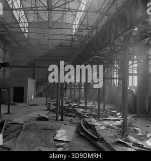 Sloviansk, Ukraine, USSR, 1960s. An archival interior view of a workshop under construction at the Armaturno-Izolyatorny Zavod (AIZ). The vast industrial hall features high steel truss ceilings with skylights and heavy vertical support beams. The floor is scattered with construction debris and raw materials. This atmospheric image captures the expansion of industrial capacity and the scale of engineering works in the peaceful Donbas region during the Soviet era. Stock Photo