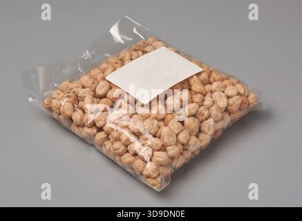 transparent plastic bag of dried chickpeas with blank white label, sealed packet mockup isolated neutral gray background, legumes packaging template Stock Photo