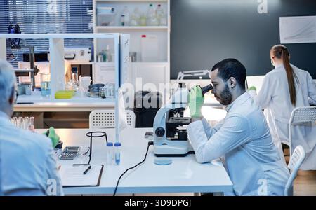 Young Adult Man Using Microscope in Modern Scientific Laboratory Stock Photo